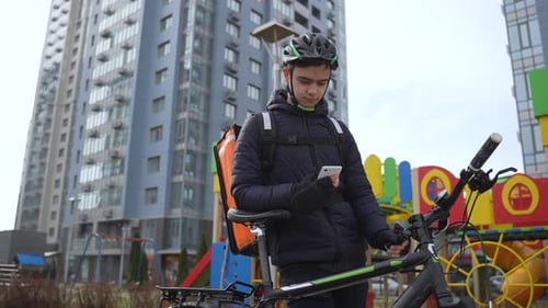 Delivery Person on Bicycle with Smartphone in City