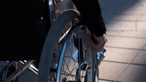 Rear View of a Man in Wheelchair Near Business Centre with Focus on Hand