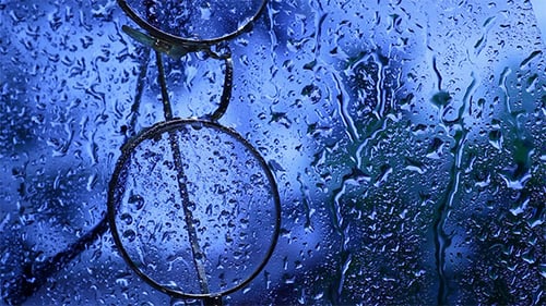 Rainy Window View with Eyeglasses Close-Up
