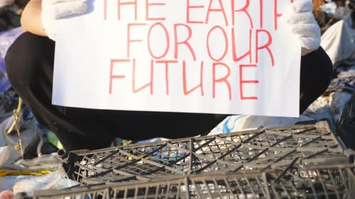 Young Adult Protesting in Landfill Holding Sign