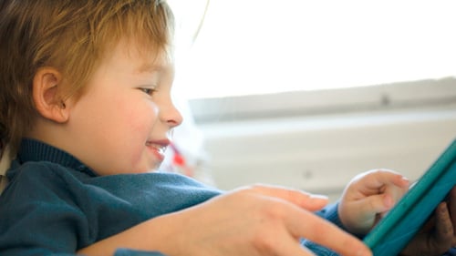 Boy In The Train Using Touchpad Held By Mother