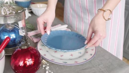 Woman Sets Festive Holiday Table with Plates