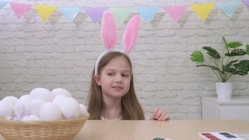 Funny Girl with Bunny Ears Peeking Out From Under the Table at Easter Ready to Hunt for Eggs