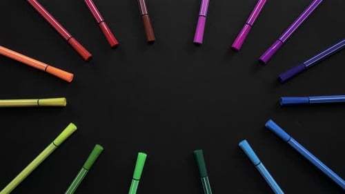 School Markers of Different Colors Are Located on the Black Surface. Stop Motion Animation with