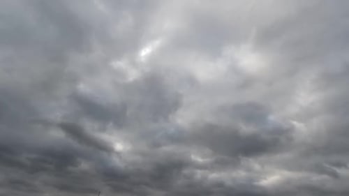 Time lapse: fluffy blue and gray clouds are floating by the sky.
