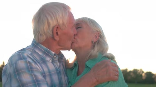 Senior Couple Sharing Loving Kiss Outdoors at Sunset