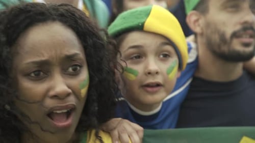 Brazilian soccer fans watching match at stadium with look of disappointment