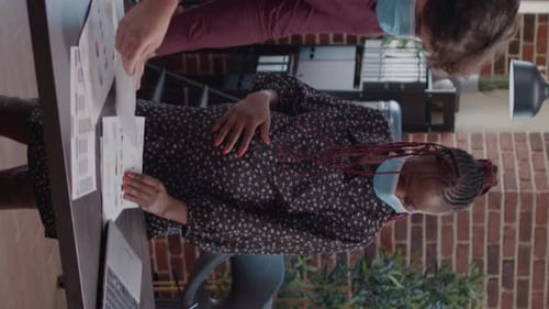 Vidéo verticale Employée enceinte travaillant avec un homme sur des graphiques commerciaux