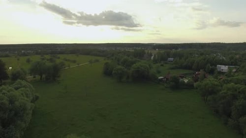 View of Forest, Lake and Country Houses Against Blue Sky with Sun and Clouds in Sunset at Summer