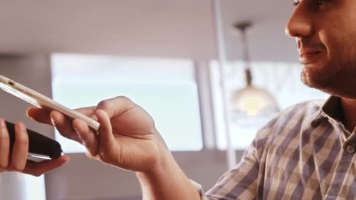 Young Adult Pays With Mobile Phone In Store