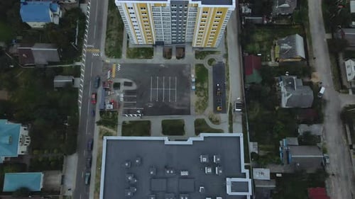 City block. Modern multi-storey buildings among cottages. Flying at dusk at sunset.