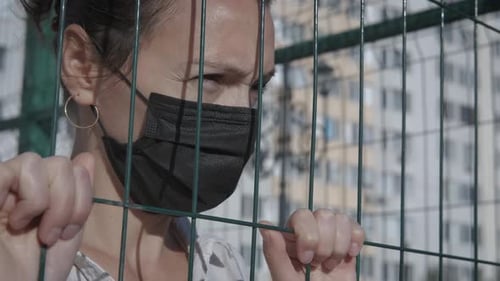 Woman in quarantine by bars.