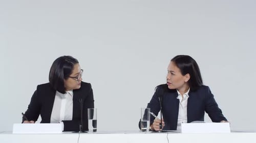 Two Women Signing Documents at a Table