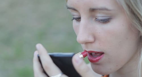 Schönes Mädchen malt Lippen