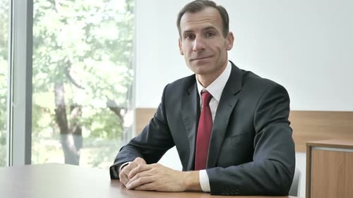 Businessman Smiling While Sitting at Office Desk