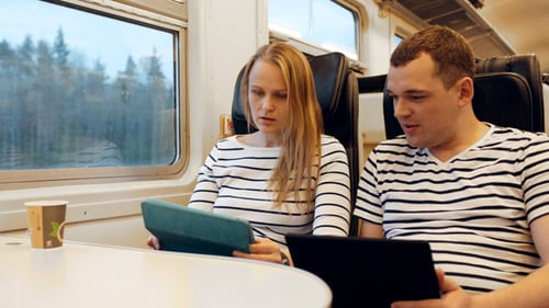 Couple Using Tablets on a Modern Train
