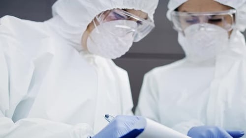 People in Protective Suits Reviewing Documents