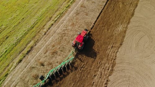 Tractor with Multi-plow on Farmland in Sunny Weather in Spring and Autumn. Plowing the Soil for