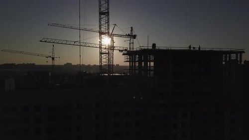 Chantier au coucher du soleil. Silhouette d'une grue de chantier près du bâtiment