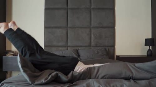 Tired Person After a Hard Day at Work Falls on the Bed with His Eyes Closed and Sleeps in Slow