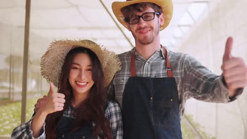 Smiling Farmers Thumbs-Up in Sunny Greenhouse