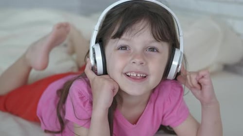 Girl Lying on Bed Listening to Music Headphones