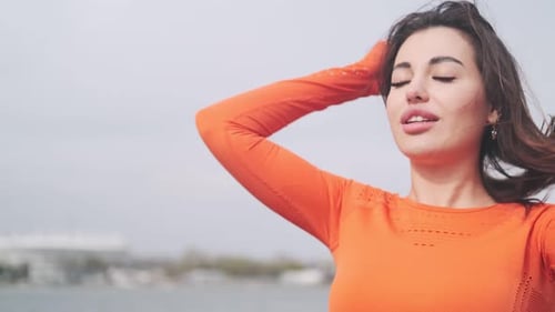 Woman Touching Hair in Orange Shirt Outside