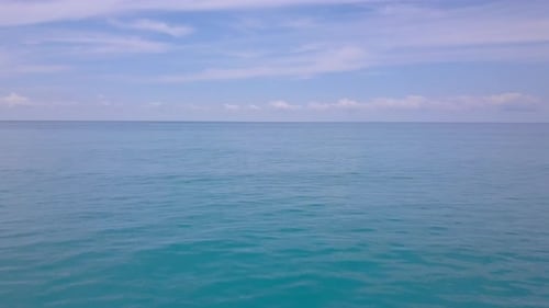 Luftaufnahme fliegt über türkisfarbene Meereswellen, Drohnenkamera bewegt sich langsam tief über der blauen Wasseroberfläche
