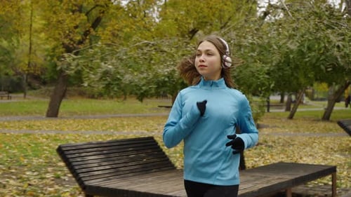 Jogger with Headphones Running in Park in Slow Motion