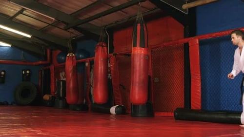 Man Practicing Karate in Gym with Punching Bag