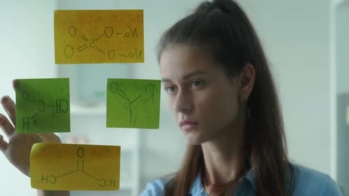 Woman Looks at Chemical Diagrams on Sticky Notes