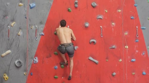 Shirtless Man Climbing an Indoor Rock Wall