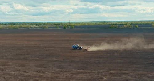 Old Farm Tractor is Loosening Soil and Plowing Land of Agricultural Field View From Drone Prores