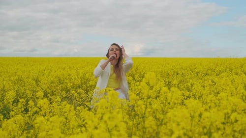 A Beautiful Woman Dances Looks at the Camera and Sings Standing in a Yellow Field. Female Singer