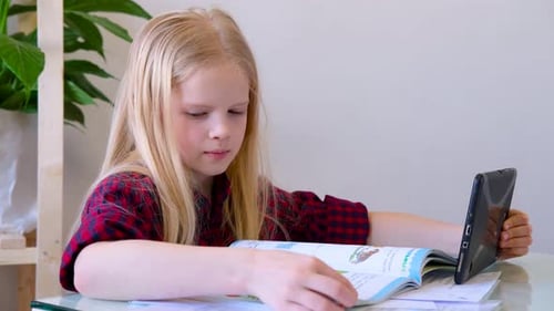 Young Girl Studies with Book and Tablet Indoors