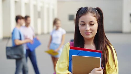 Student Standing with Books Near College