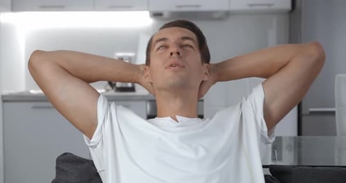 Man Relaxing in Modern Kitchen with Hands Behind Head