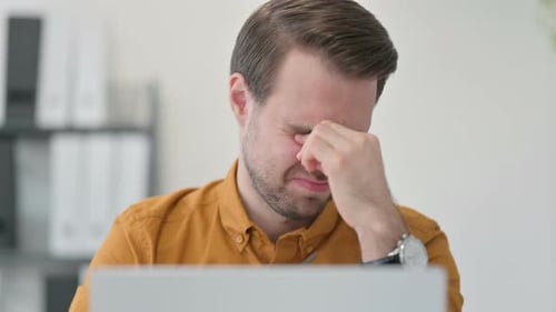 Close Up of Young Man with Laptop Having Headache in Office