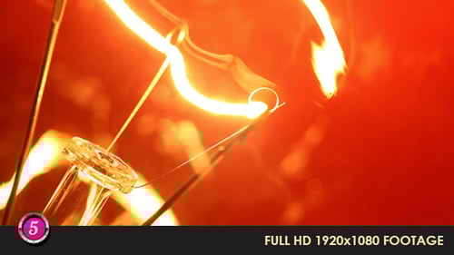 Glowing Light Bulb Filament Close Up on Orange