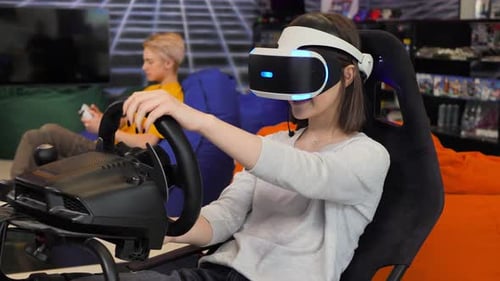 Teenager-Mädchen mit Virtual-Reality-Brille, die sich am Lenkrad festhält und Computer spielt