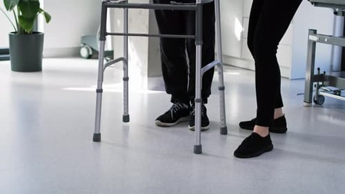 Man Uses Walker with Physical Therapy Support