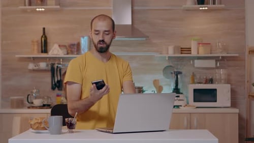 Man Working on Laptop in Kitchen at Night