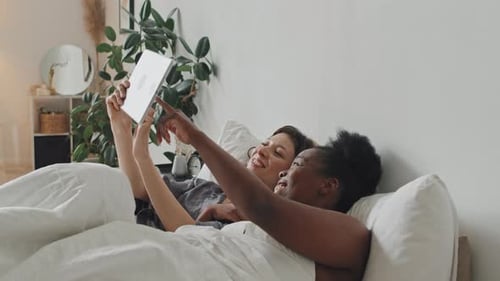 Couple Lying in Bed Using Tablet Together