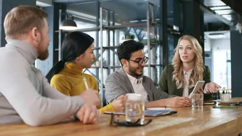 Multiracial Business Partners Sitting and Talking at Bar Counter in Cafe