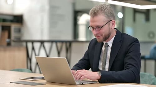 Excited Businessman Celebrating Success on Laptop in Office