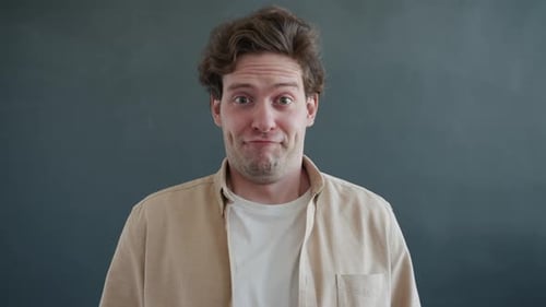 Portrait of Silly Guy Making Funny Faces Showing Tongue on Gray Color Background