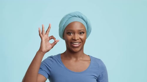 Afroamerikanerin gestikuliert und sagt OK auf blauem Hintergrund