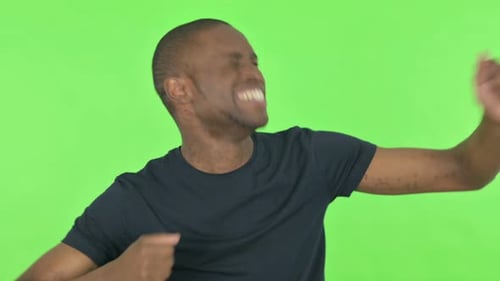 Happy Young African Man Dancing on Green Background