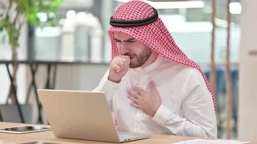 Sick Arab Businessman with Laptop Coughing in Office