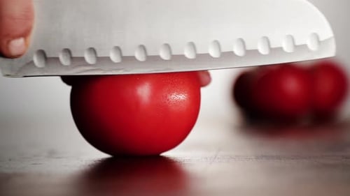 Sharp Knife Slicing a Fresh Red Tomato